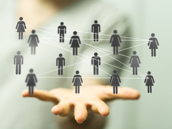 KI-Grafik: eine offene Handfläche über der symbolisch ein Netzwerk aus männlichen & weiblichen Figuren schwebt