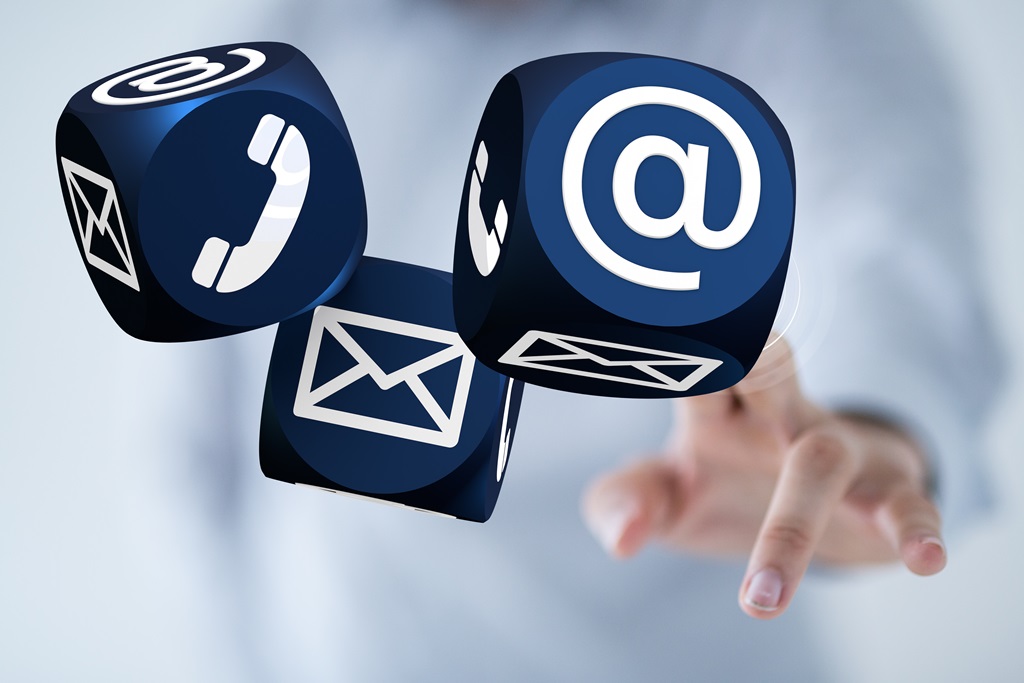 Drei Würfel, die die Symbole Telefon, E-Mail und @-Zeichen zeigen und eine Hand die die Würfel antippt